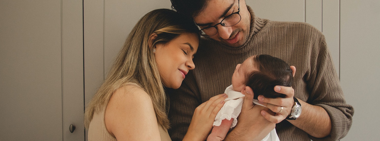 Eltern mit Baby auf dem Arm erhalten Glückwünsche zur Geburt
