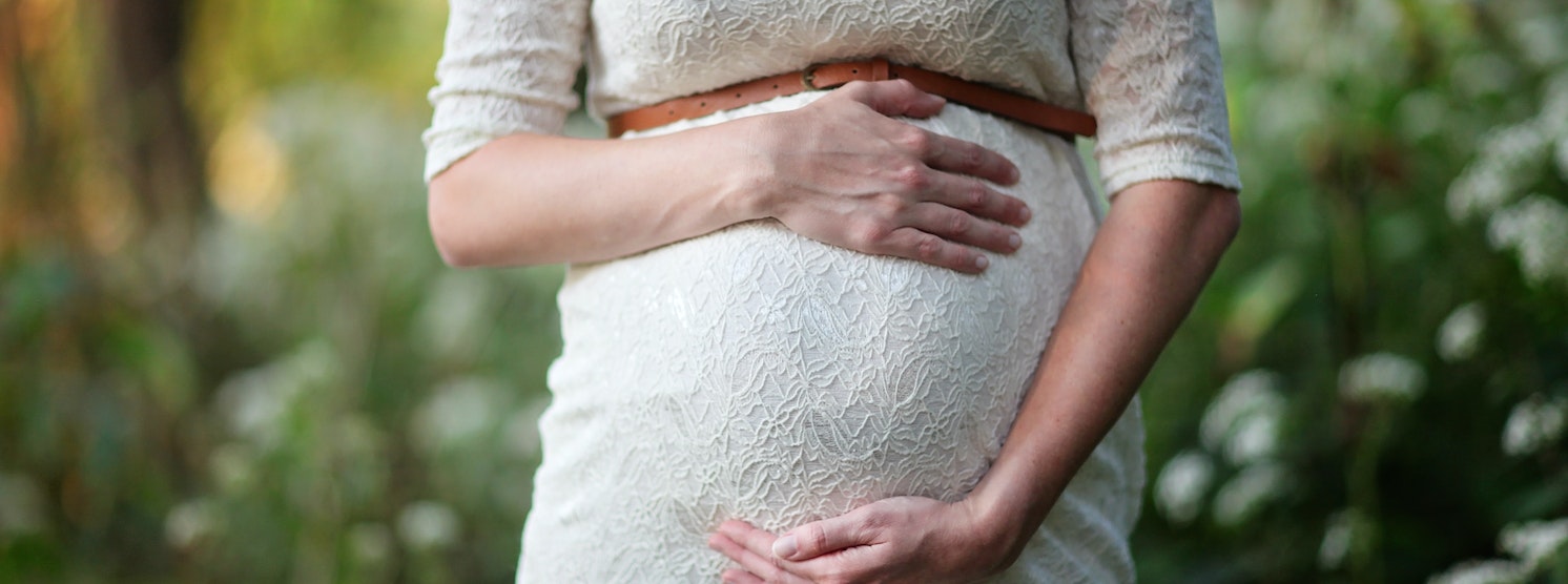Schwangere Frau, die sich Hände vor den Bauch hält
